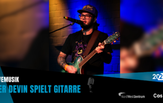 Der Devin spielt Gitarre auf der Bühne.